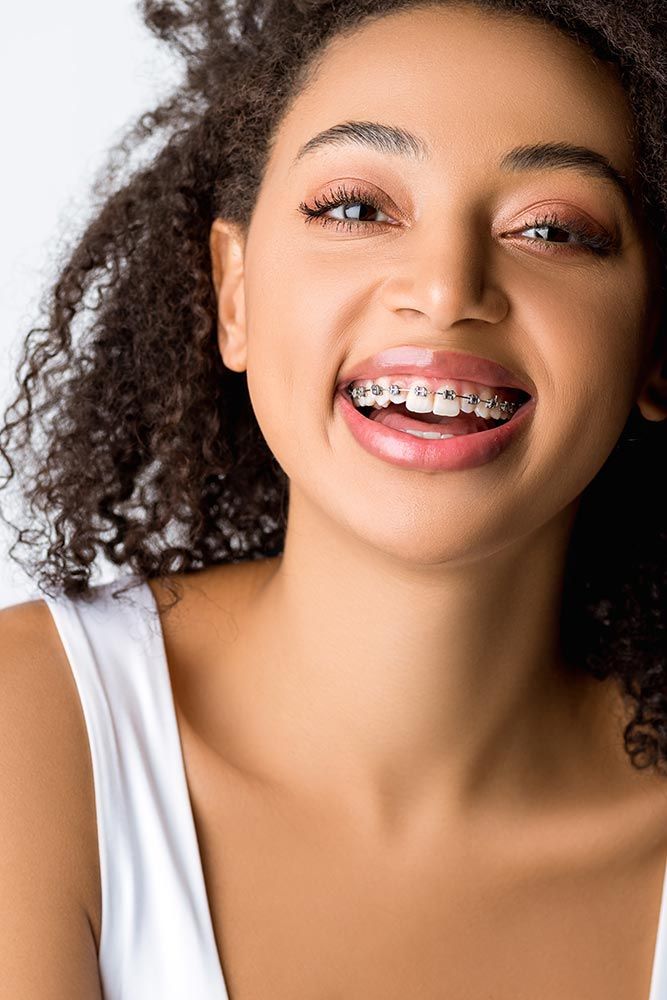 Lachendes afroamerikanisches Mädchen mit Zahnspange, isoliert auf grau